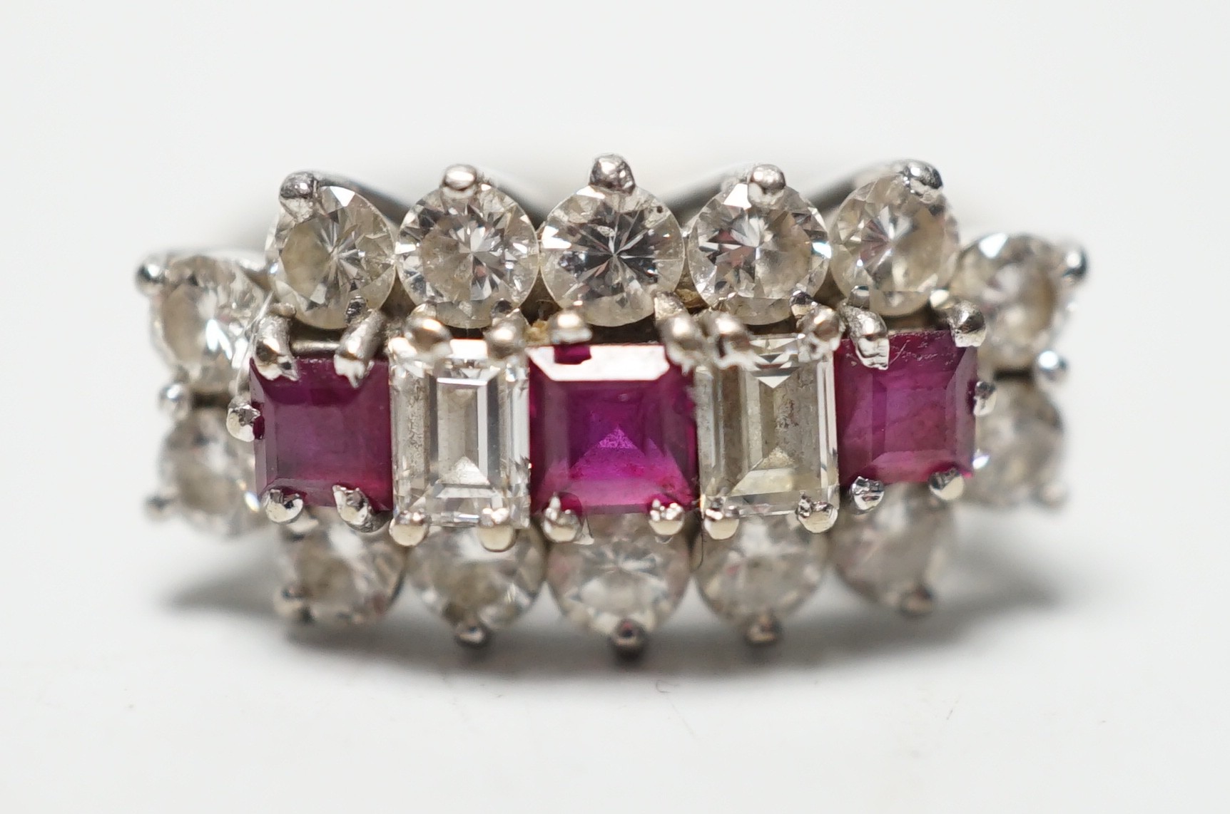A modern 18ct white gold, square cut ruby and round and baguette cut diamond set cluster ring, size L, gross weight 3.9 grams.
